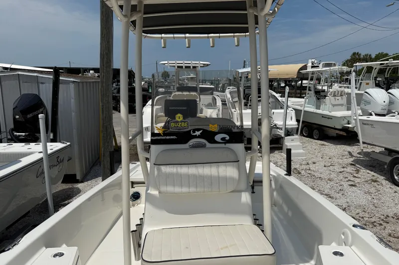 Slide: The Image of 2017 Mako 19 CPX boat interior with seating and console, parked among other boats. - 8