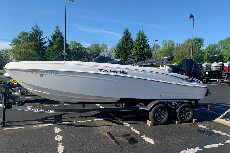 The Image of 2023 Tahoe T21 boat on trailer in parking lot, surrounded by trees. - 0
