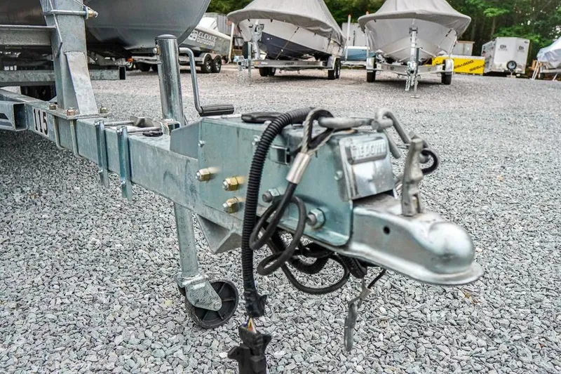 Slide: The Image of Trailer hitch of a 2012 Xcursion X21C boat on gravel lot with covered boats. - 27