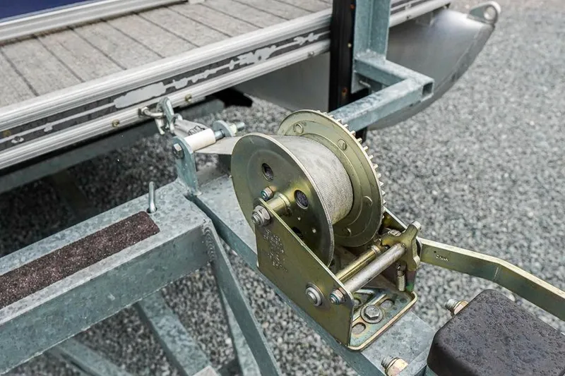 Slide: The Image of Winch mechanism on a 2012 Xcursion X21C boat trailer, parked on gravel. - 29