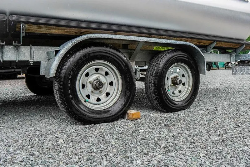 Slide: The Image of Trailer wheels of a 2012 Xcursion X21C boat on gravel surface. - 31
