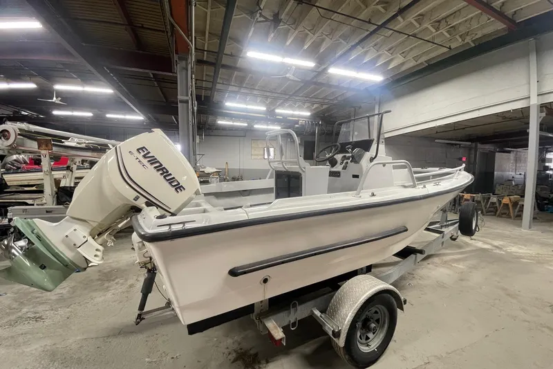 Slide: The Image of 1995 Boston Whaler Justice boat with Evinrude engine in a warehouse setting. - 2
