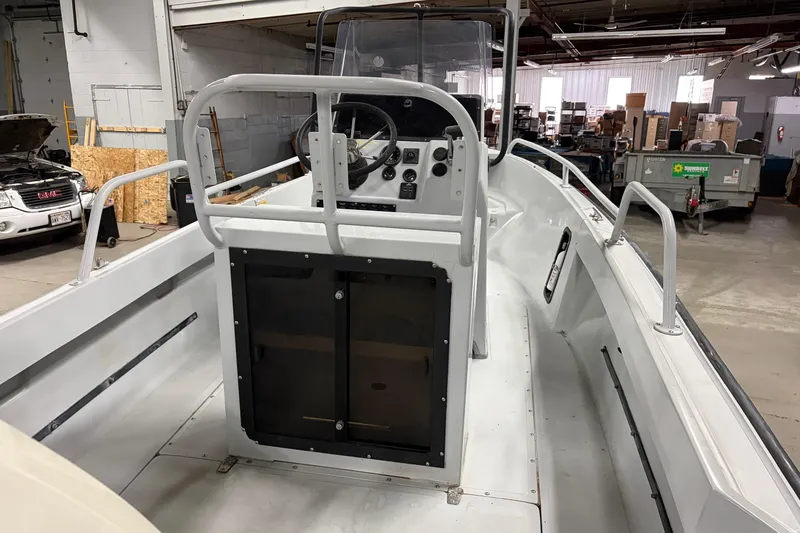 Slide: The Image of 1995 Boston Whaler Justice boat interior with steering console in a warehouse setting. - 8