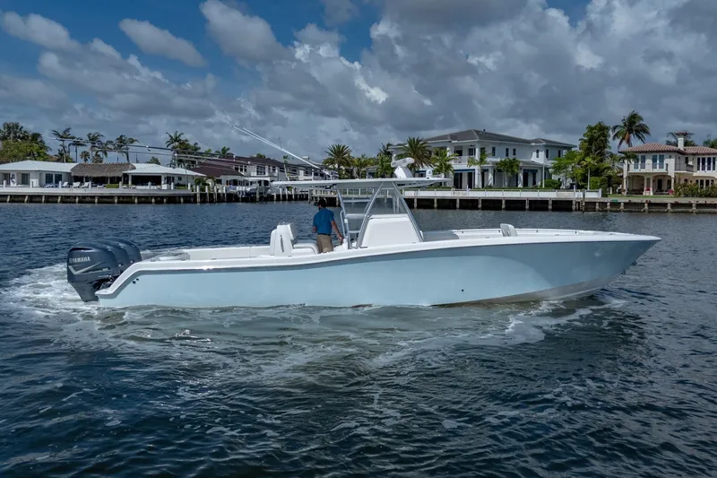 The Image of 2017 Invincible 39 Open Fisherman boat cruising near waterfront homes under cloudy skies. - 0