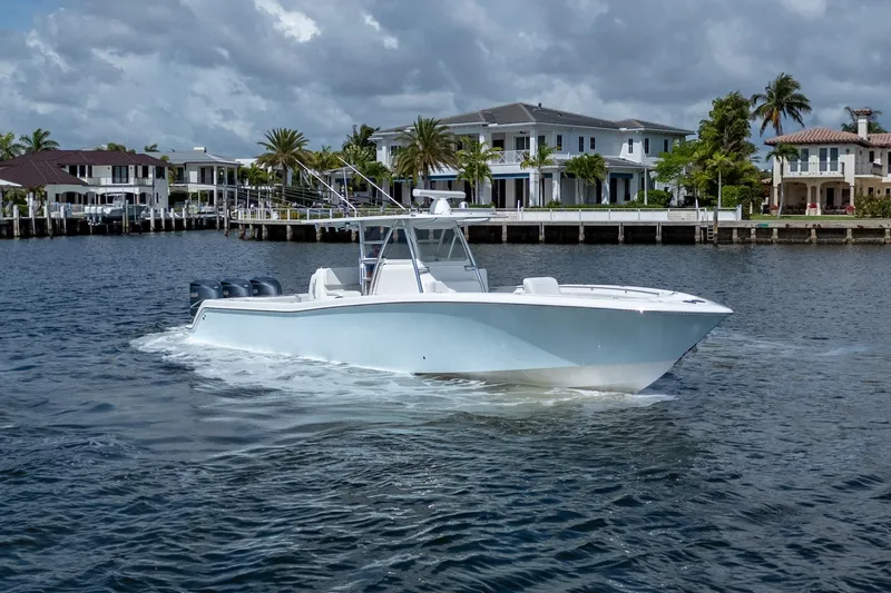 Slide: The Image of 2017 Invincible 39 Open Fisherman boat cruising near waterfront homes under cloudy skies. - 5