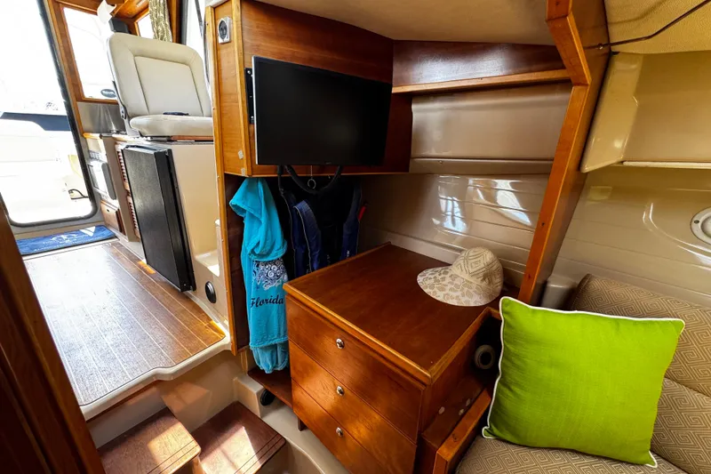 Slide: The Image of Interior of 2012 Cutwater C-26 boat with wooden cabinetry, TV, and seating area. - 19