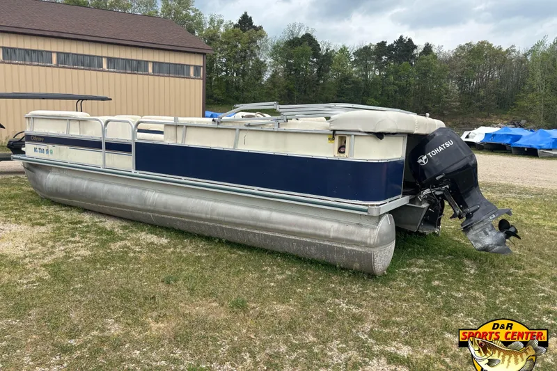 Slide: The Image of 2002 Odyssey Pontoons 2303L boat with Tohatsu motor, parked on grass near a building. - 4