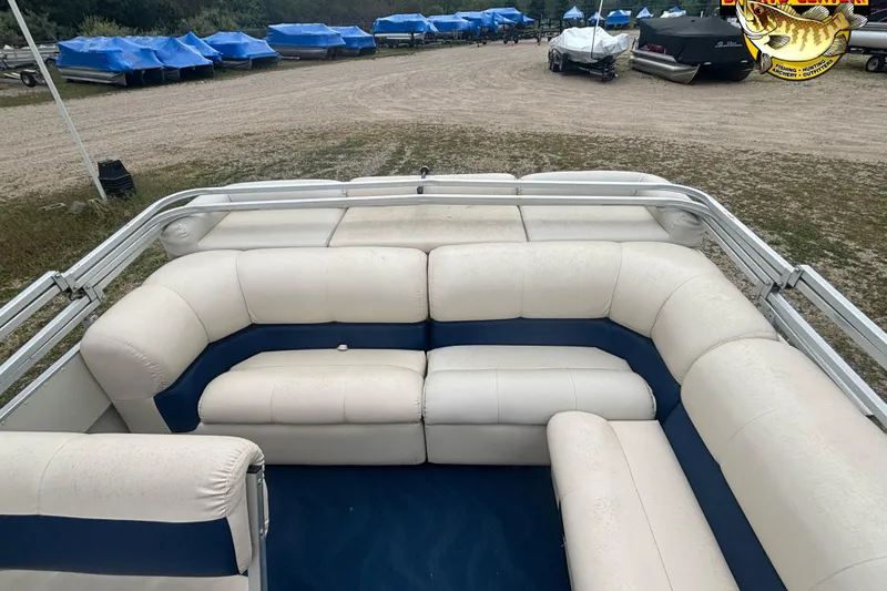 Slide: The Image of 2002 Odyssey Pontoons 2303L with white and blue seating, parked outdoors. - 8