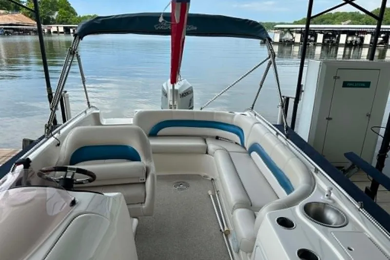 Slide: The Image of 2006 Hurricane FunDeck GS 232 OB boat interior with seating and steering wheel, docked by a lake. - 17