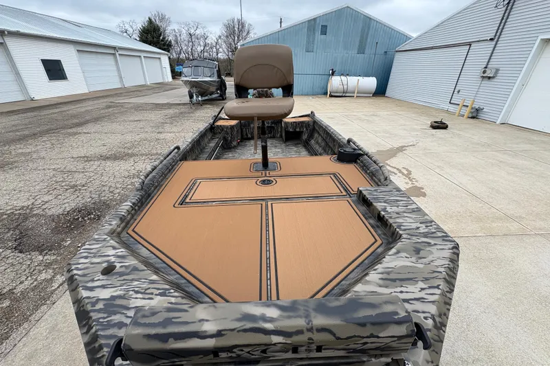 Slide: The Image of 2026 Excel 1860 F4 Pro boat with camo design and tan seating, parked outdoors. - 8