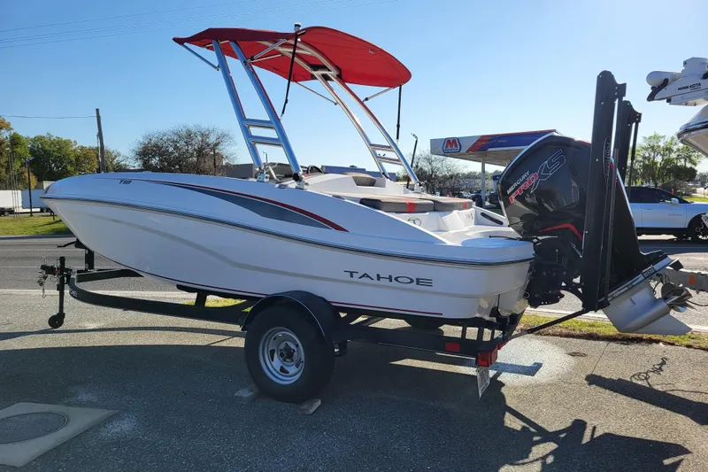 Slide: The Image of 2023 Tahoe T18 boat with red canopy and Mercury engine on trailer. - 2