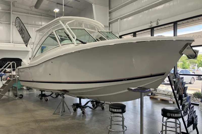 The Image of 2026 Albemarle 27 Dual Console boat displayed in a showroom with Yamaha stools. - 1