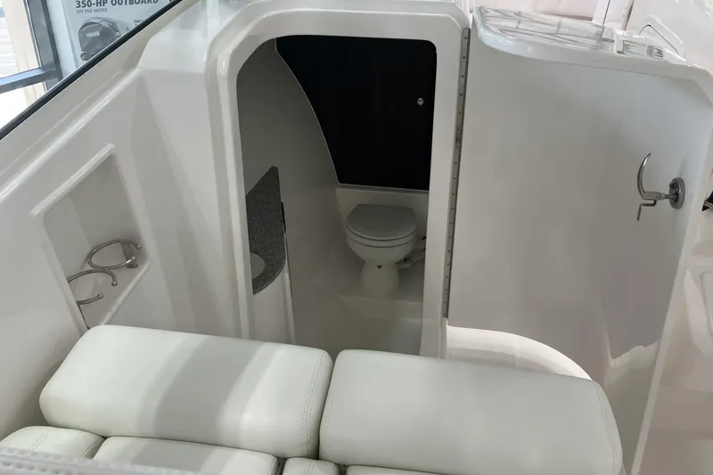 Slide: The Image of 2026 Albemarle 27 Dual Console boat interior with compact bathroom and seating area. - 6