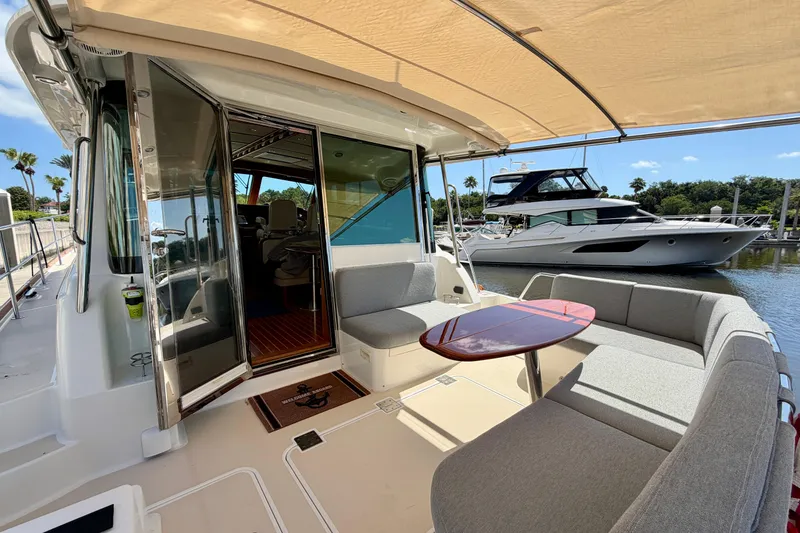 Slide: The Image of 2016 Sabre 48 Salon Express yacht with outdoor seating and table, docked by the water. - 14