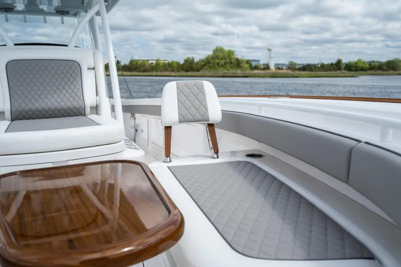Slide: The Image of 2025 Valhalla Boatworks V-33 interior with elegant seating and wooden table, near water. - 11