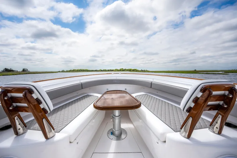 Slide: The Image of 2025 Valhalla Boatworks V-33 interior with elegant seating and wooden accents on a serene waterway. - 12