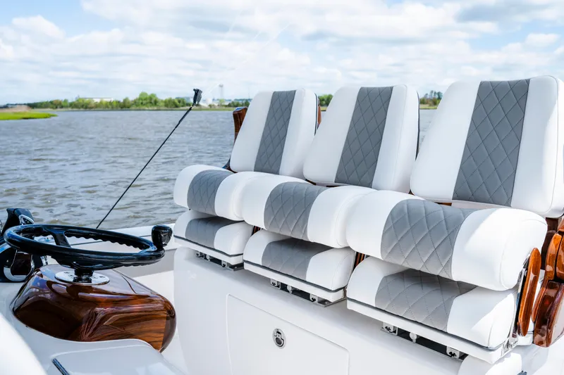 Slide: The Image of 2025 Valhalla Boatworks V-33 helm with luxurious seating and steering wheel on a calm waterway. - 33
