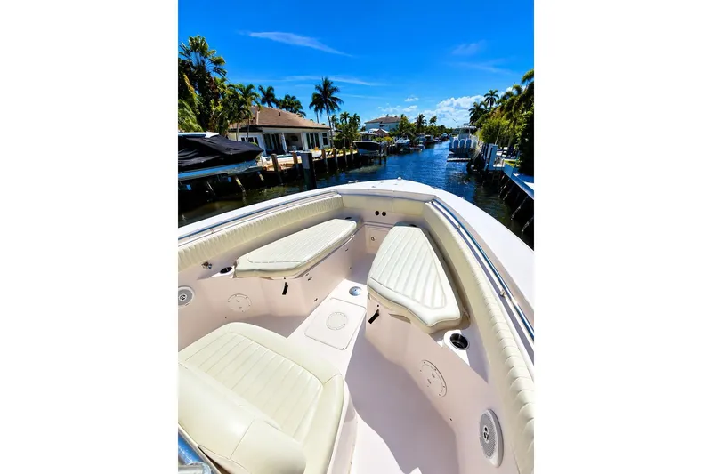 Slide: The Image of 2014 Grady-White Canyon 306 boat interior with seating, docked in a scenic canal. - 12