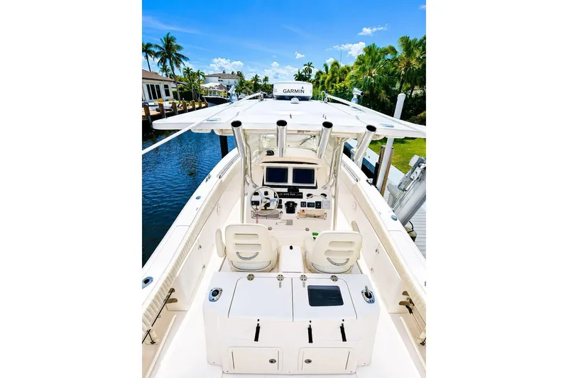 Slide: The Image of 2014 Grady-White Canyon 306 boat interior with helm, electronics, and seating, docked by a canal. - 7