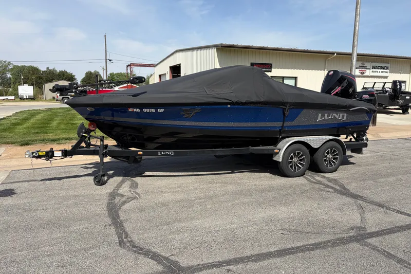 Slide: The Image of 2024 Lund 202 Pro-V GL boat on trailer, covered, parked outside dealership. - 7