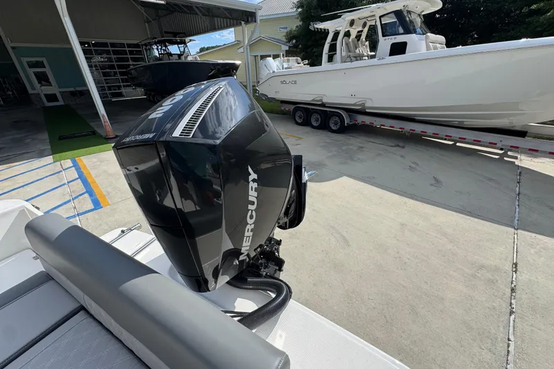 Slide: The Image of 2027 Sea Born LX22 Center Console with Mercury engine, parked near a larger boat. - 33