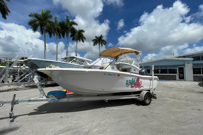 The Image of 2022 Tidewater 198 CC Adventure boat on trailer, parked outdoors under palm trees. - 0