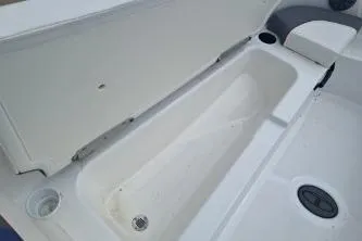 Slide: The Image of 2023 Tahoe T18 boat storage compartment, open lid, white interior, sleek design. - 12