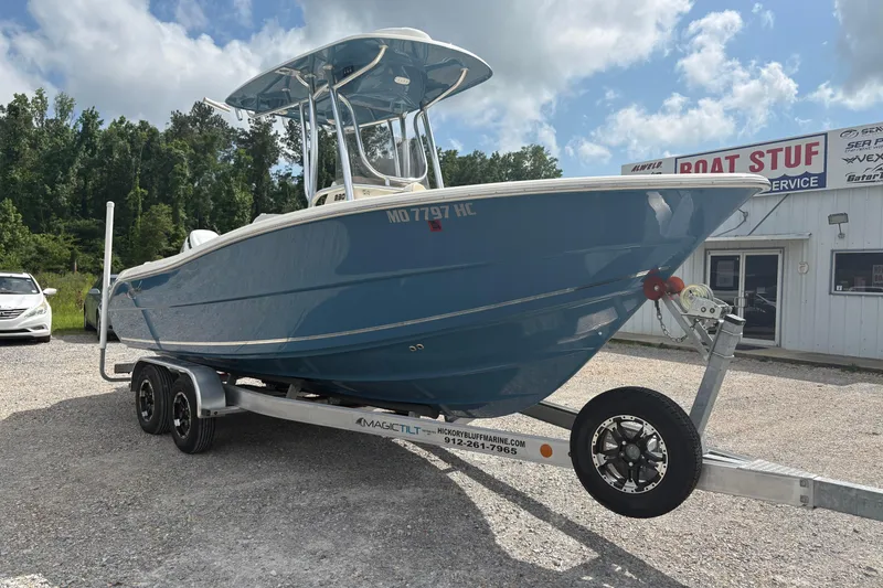 Slide: The Image of 2024 Bulls Bay 230 Center Console boat on trailer, parked outside a marine service shop. - 3