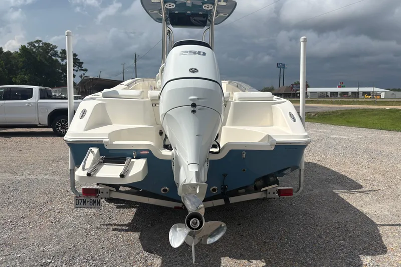 Slide: The Image of 2024 Bulls Bay 230 Center Console boat with powerful outboard motor, parked on gravel. - 7