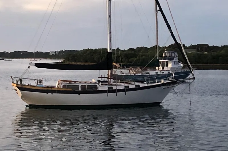 Slide: The Image of 1979 Downeast DE38 sailboat anchored on calm water with scenic background. - 3