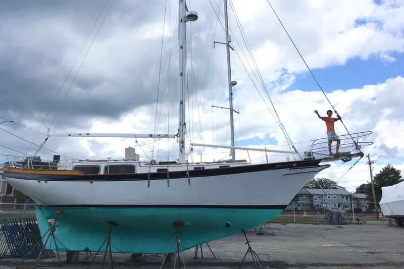 Slide: The Image of Man standing on 1979 Downeast DE38 sailboat, dry docked under cloudy sky. - 5