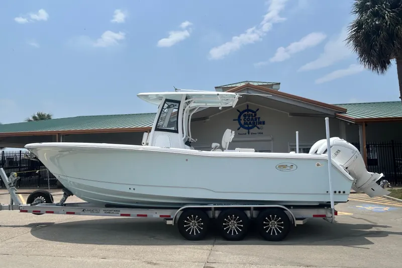 The Image of 2026 Sea Hunt Gamefish 27 Coffin Box boat on trailer, parked outside a marine shop. - 0