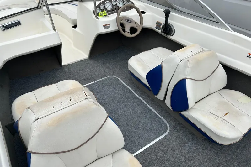 Slide: The Image of 2003 Bayliner 175 Bowrider interior with white and blue seating, steering wheel, and dashboard. - 10
