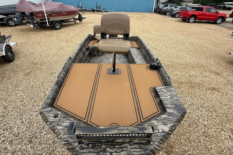 Slide: The Image of 2026 Excel 1860 Viper F4 boat with camouflage design and seating, parked on gravel. - 8