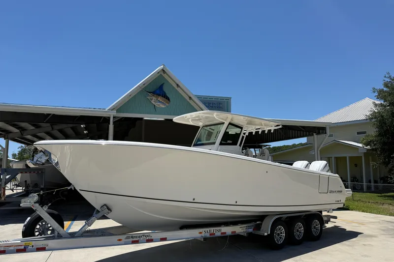 The Image of 2026 Sailfish 312 CC boat on trailer, parked near a marine building. - 1