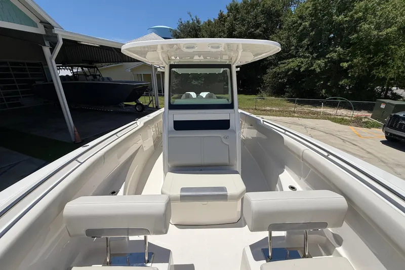 Slide: The Image of 2026 Sailfish 312 CC boat interior with seating and console, parked outdoors. - 21