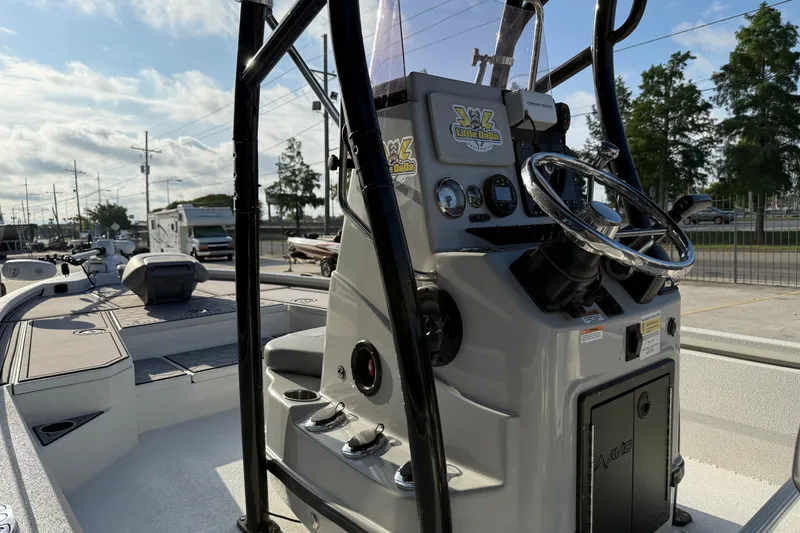 Slide: The Image of 2022 Avid 23 FS Magnum boat console with steering wheel and controls, parked outdoors. - 14