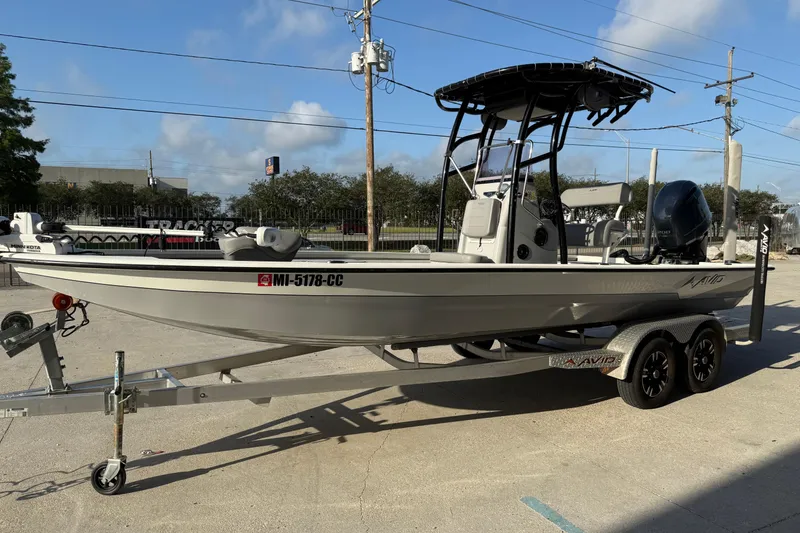 Slide: The Image of 2022 Avid 23 FS Magnum boat on trailer, parked outdoors under clear sky. - 15