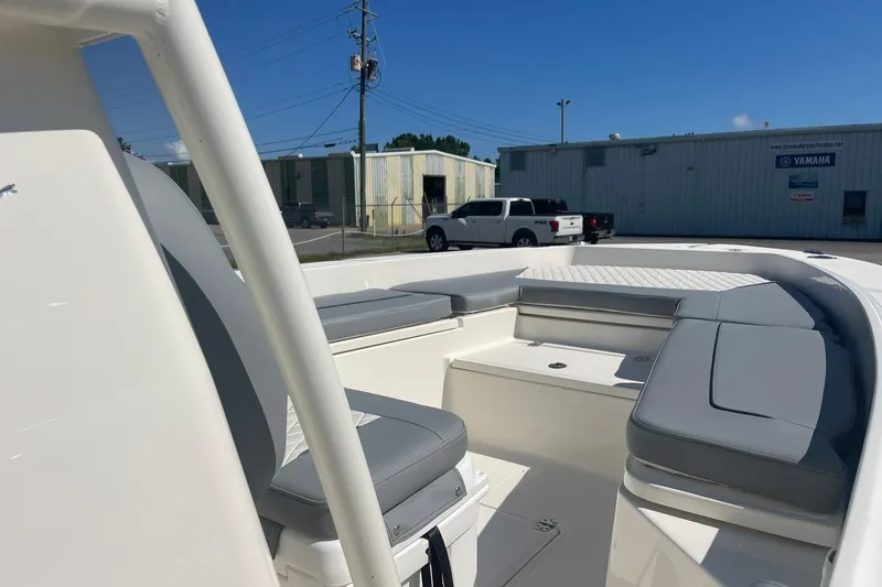 Slide: The Image of 2026 Pioneer 220 Bay Sport boat interior with cushioned seating, parked near industrial buildings. - 18