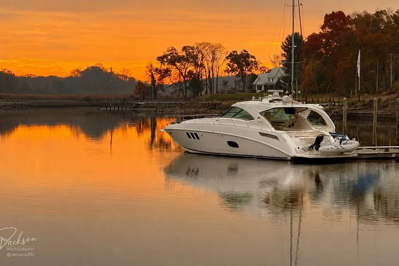 The Image of 2012 Sea Ray Sundancer 540 yacht docked at sunset with vibrant orange sky. - 0