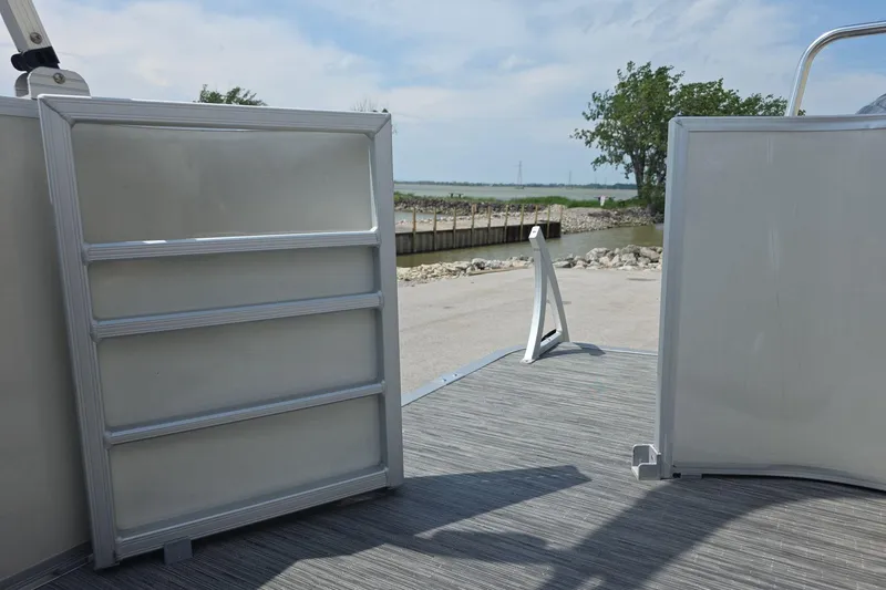 Slide: The Image of 2022 Bennington L 21 L-Bench pontoon boat with open gate, near water. - 11