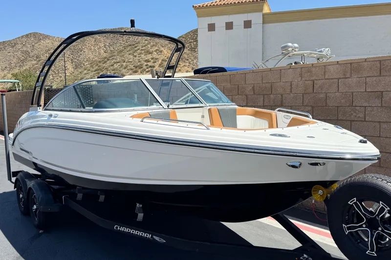 Slide: The Image of 2023 Chaparral 23 SSi boat on trailer, parked outdoors with scenic background. - 1