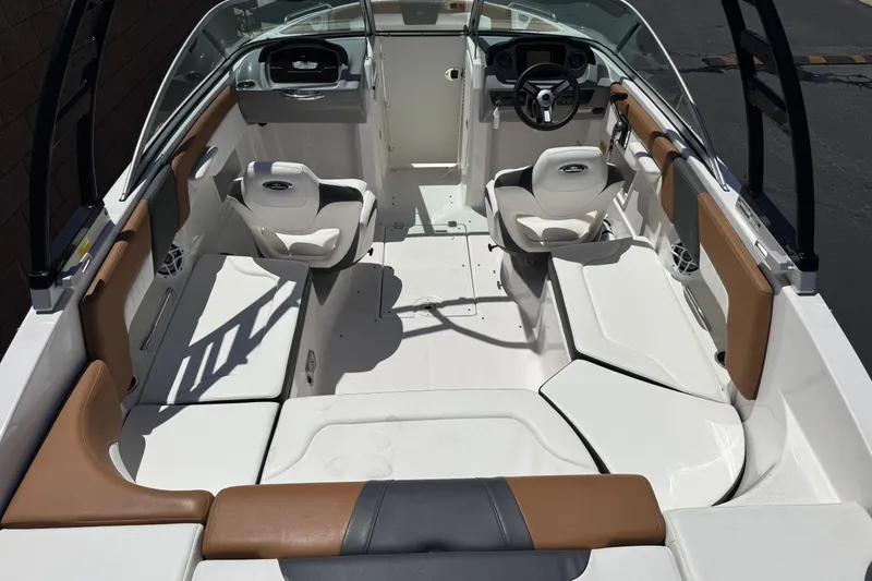 Slide: The Image of 2023 Chaparral 23 SSi boat interior with white and brown seating, steering wheel, and dashboard. - 10