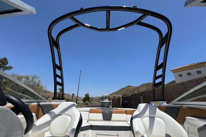 Slide: The Image of 2023 Chaparral 23 SSi boat interior with wakeboard tower, under clear blue sky. - 17
