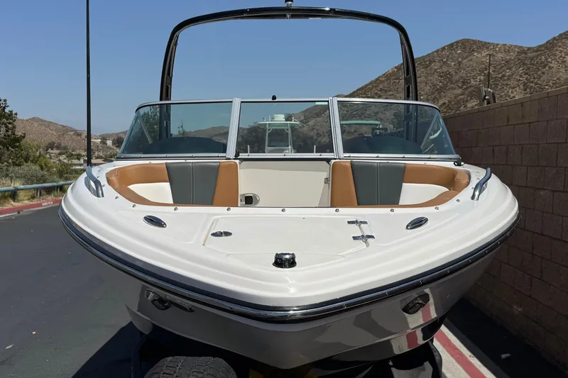Slide: The Image of 2023 Chaparral 23 SSi boat with sleek design, parked outdoors against a mountainous backdrop. - 2