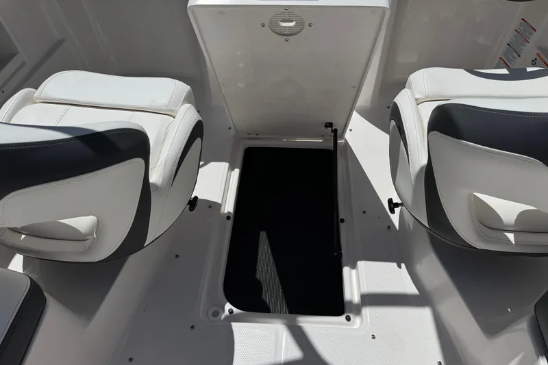 Slide: The Image of 2023 Chaparral 23 SSi boat interior with open storage compartment and cushioned seats. - 23