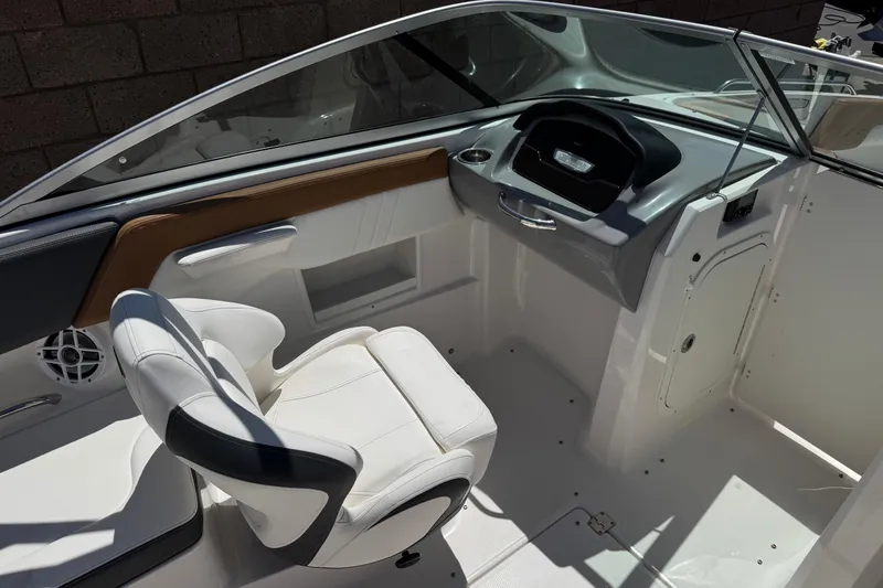 Slide: The Image of 2023 Chaparral 23 SSi boat interior with white seating and modern dashboard design. - 25
