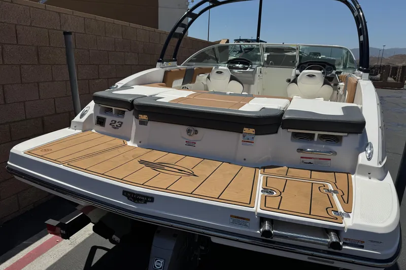 Slide: The Image of 2023 Chaparral 23 SSi boat with spacious deck and seating, parked outdoors. - 6