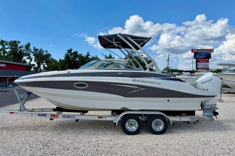 The Image of 2023 Crownline Eclipse E235 XS boat on trailer, displayed outdoors under blue sky. - 0