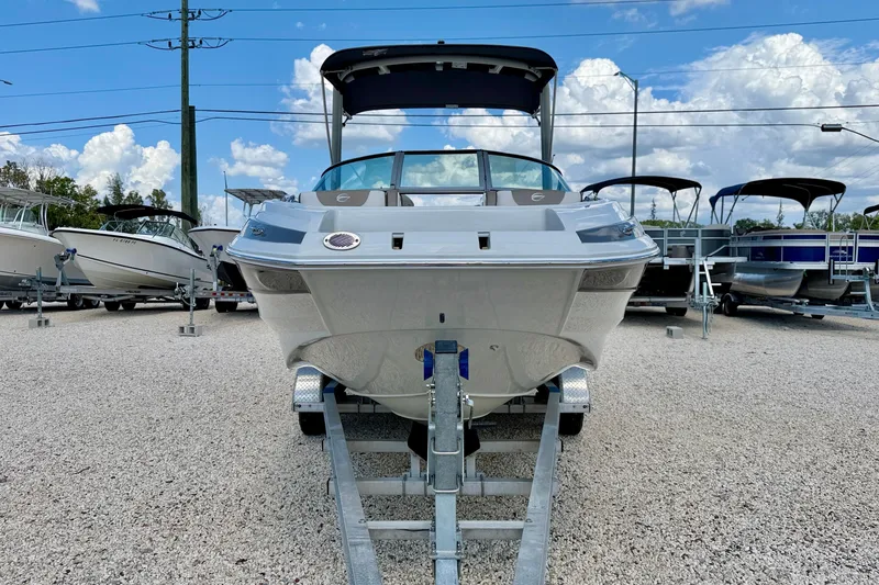 Slide: The Image of 2023 Crownline Eclipse E235 XS boat on trailer, displayed outdoors under blue sky. - 2